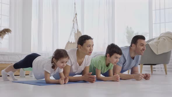 Sport Family Standing in Plank During Yoga Workout