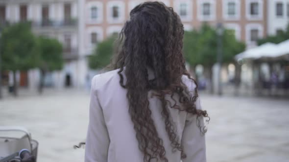 Moroccan Woman With Long And Curly Hair Walking On City Park At Daytime