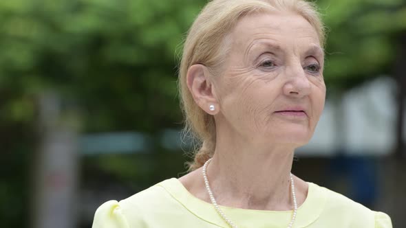 Beautiful Happy Senior Businesswoman Smiling While Thinking Outdoors