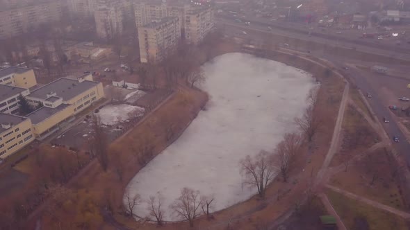 Melting frozen lake against the backdrop of the city in the fog