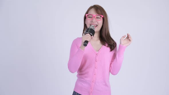 Young Happy Asian Nerd Woman Singing with Microphone