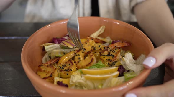 Woman Eats Fresh Salad with Shrimps and Lemon in Cafe