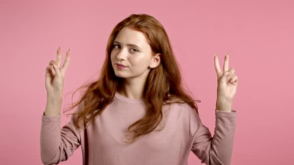 Pretty Girl Showing with Hands and Two Fingers Like Quotes Gesture, Bend Fingers Isolated Over Pink