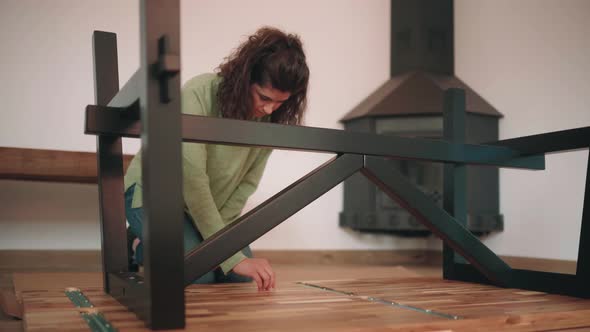 Woman Removing Sticker Residue On The New Assembled Wooden Table - high angle shot
