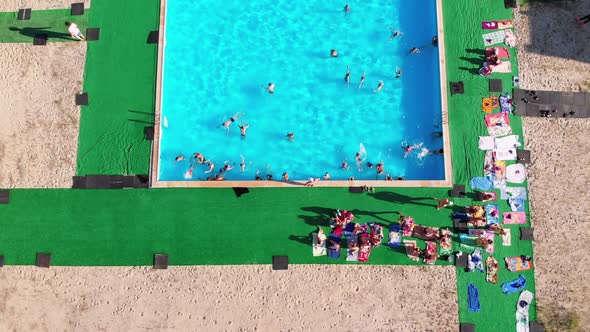 Flight Over the Blue Pool with People on Vacation. Aerial View on Clean Swimming Pool