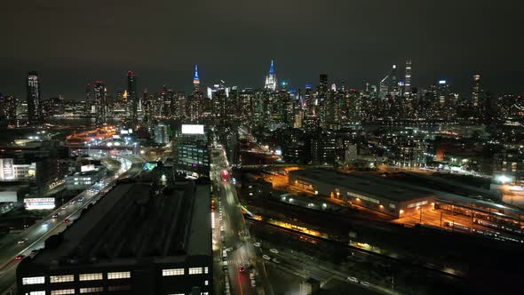 An aerial view from over Long Island City, New York at night. The drone camera slowly truck left and