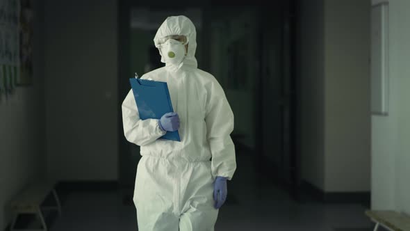 Handheld video of worker in protective suit walking down the hall. Shot with RED helium camera in 8K