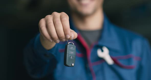 Cheerful Unrecognizable Auto Mechanic Giving Car Keys To Camera After Finishing Vehicle Maintenance