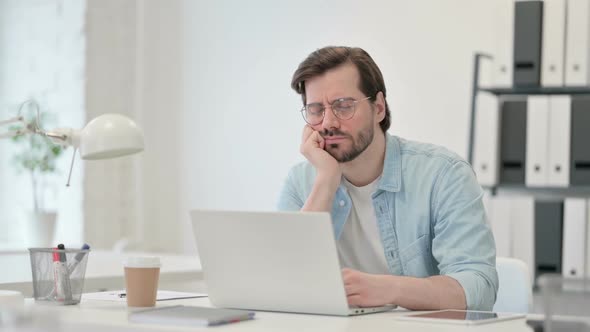 Young Man with Laptop Taking Nap at Work