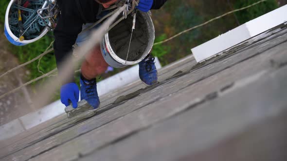 Industrial Climber Suspended on Ropes Insulates Facade with Styrofoam Near Wall