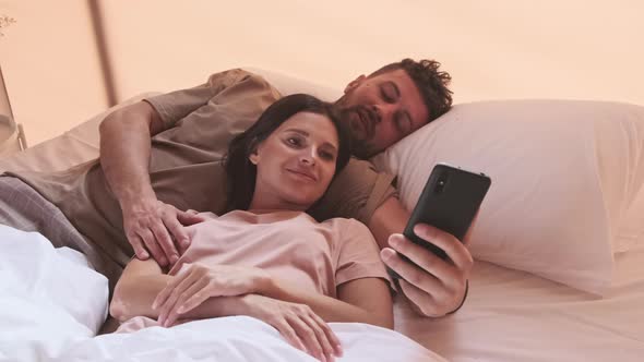 Couple Using Smartphone in Bed