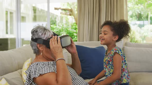 Grandmother and granddaughter using virtual reality headset at home