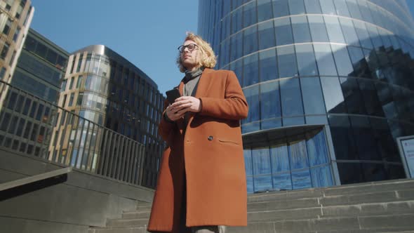 Businessman Walking in Downtown and Using Smartphone