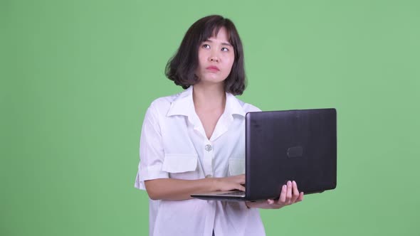 Happy Beautiful Asian Businesswoman Thinking While Using Laptop