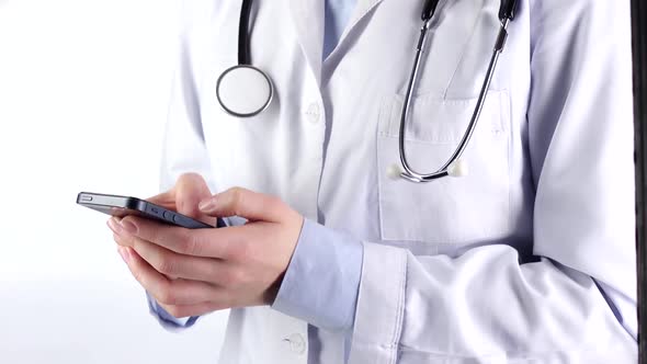 Doctor Standing, Holding and Typing on Mobile Phone, Wearing Stethoscope, White