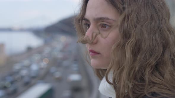 Closeup of Sad Desperate Young Beautiful Suicidal Woman Standing on Bridge with Cars Riding on Road