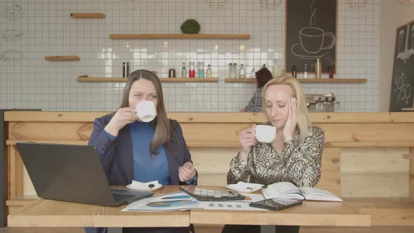 Businesswomen Drinking Coffee Talking in Cafeteria