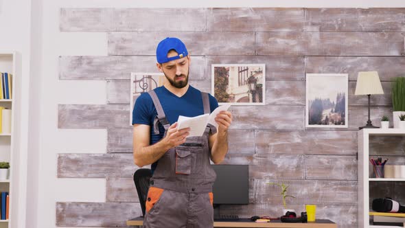 Male Worker in Coveralls Being Confused While Reading Intructions