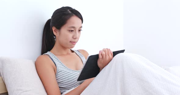 Woman watching tablet on bed