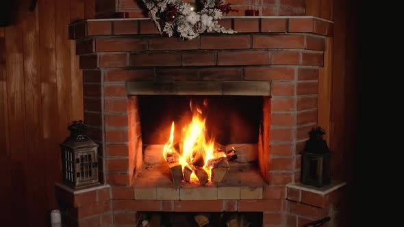 flame of fire burns in brick home Christmas fireplace.