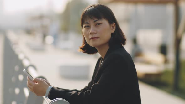 Portrait of Asian Businesswoman with Smartphone on Embankment