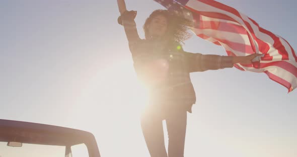 Woman standing with waving american flag on a pick up truck 4k