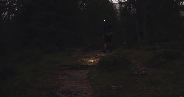 Man Walking in Forest By Night with Headlamp Light