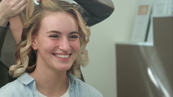 A Woman in a Hairdressing Salon Waiting To See the Results of Twisting Curls, Looking in a Mirror