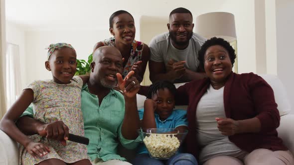 Three generation african american family cheering together while together while watching tv at home