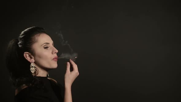 Beautiful Woman Smokes a Cigarette on a Black Background