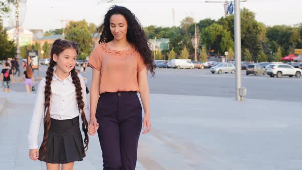 Hispanic Family Young Mother Single Parent Holds Hand of Child Daughter Schoolgirl Walk in City