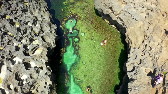 Many Travel People on the Natural Pool and Cliffs at Tropical Rock Beach Angel's Billabong, Nusa