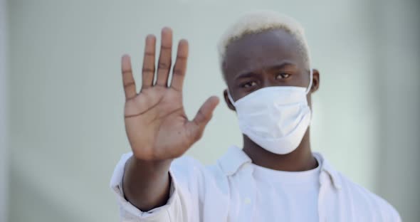 Young Ethnic Black Guy Wears Mask on Face, Protects Himself From Virus, Shows Stop Sign with Hand