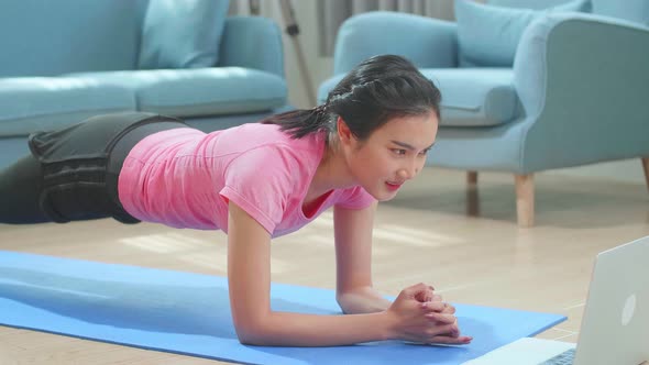 Asian Woman Doing Plank And Watching Online Tutorials On Laptop, Training In Living Room