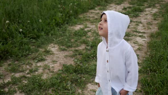 Boy in Blue Pants and a White Sweater in a Hood