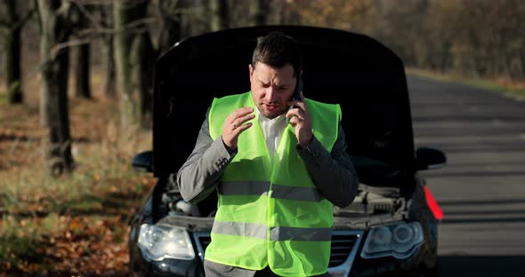 Young Sad Businessman Using Cell Phone By Brokendown Car at Countryside