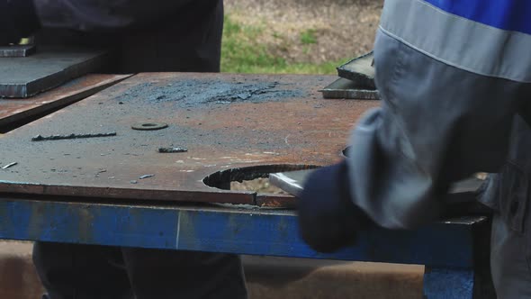 Worker on Workbench Processes Iron Sheets with Grinding Tool and Sparks Fly