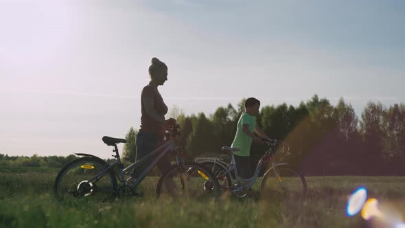 Mother and Son Ride Bicycles in the Field After the Trip