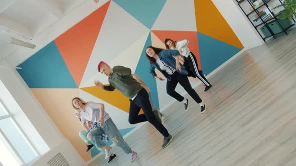 Rotating Portrait of Young Dancers Dancing in Modern Studio Training Indoors Together