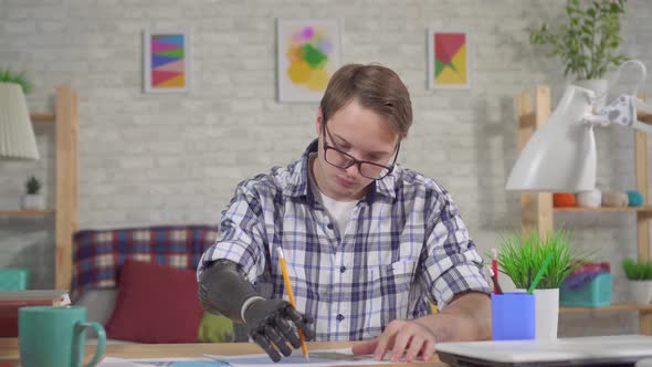 Young Man Draws a Pencil with a Bionic Prosthetic Hand