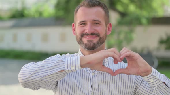 Outdoor Portrait of Middle Aged Man Showing Heart Sign By Hands