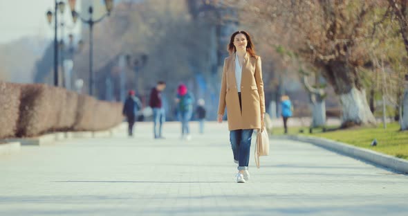 Young Brunette Woman Walks Through the Park in Early Spring