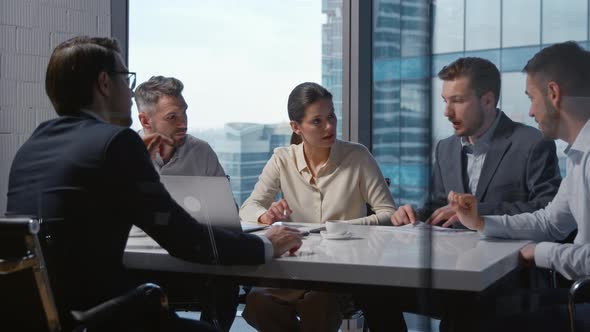 Corporate leader in a suit signing a contract with a financial company sitting at desk