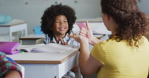 Video of happy caucasian female teacher learning math to african american boy alt