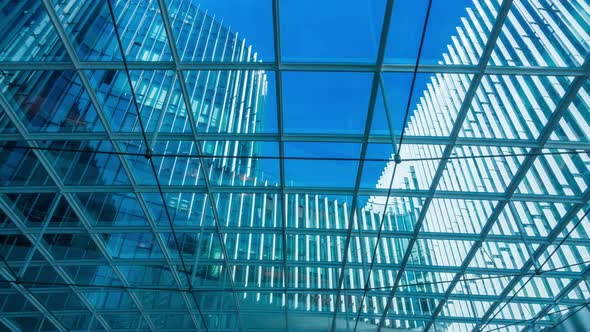 Time lapse of Looking up through the sun roof at office building at clouds and sunshine.