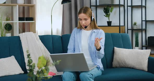 Young Light Haired Girl in Headphones Holding Video Meeting with Friend from Home 