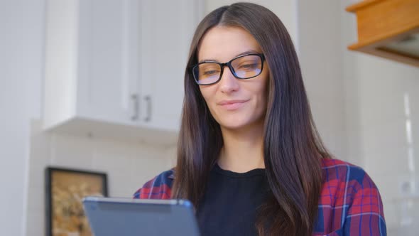 Young white woman browsing tablet computer at home with cheerful smile in 4k stock video