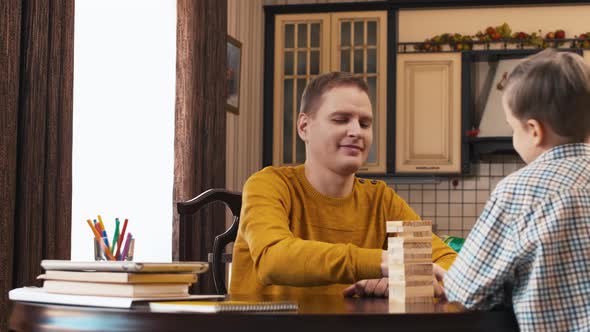 Dad playing Jenga with son at home