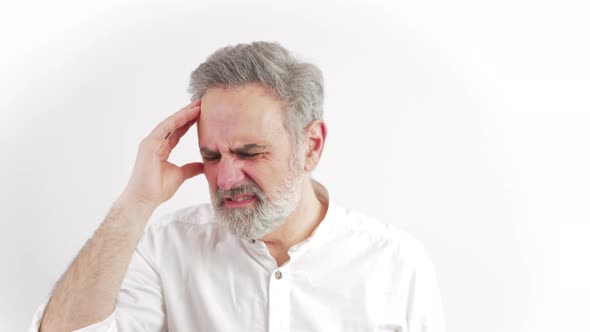 Elderly Man Suffering From a Debiitatitng Headache While Trying to Focus on Some Activity