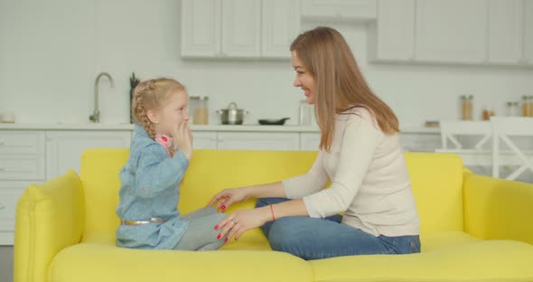 Joyful Mother and Daughter Enjoying Leisure on Sofa